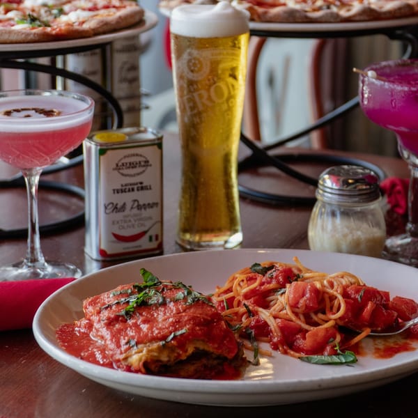 Italian meal with lasagna, spaghetti, beer, cocktails, and pizzas in the background.